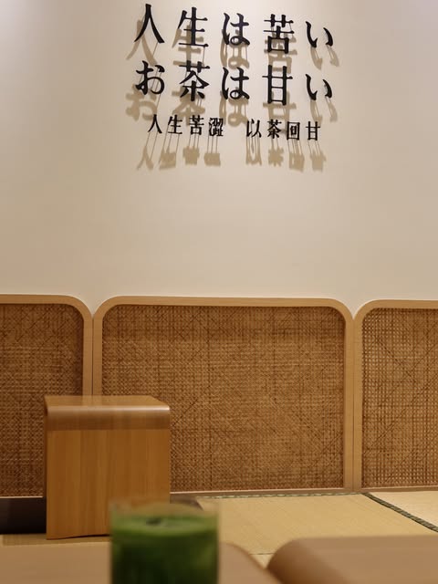 宇作茶屋的木色與藤編座位,牆上寫著人生苦澀,以茶回甘